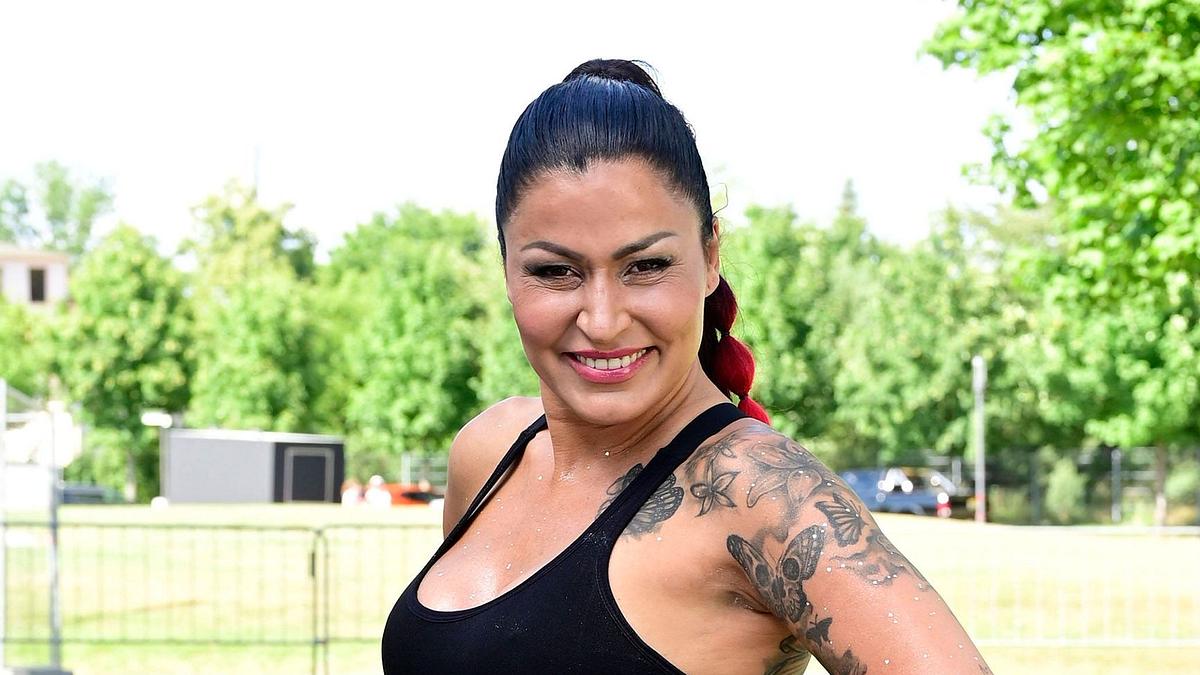 Jasmin Herren posiert lächelnd und mit einem hohen Zopf im Freien für die Kamera.