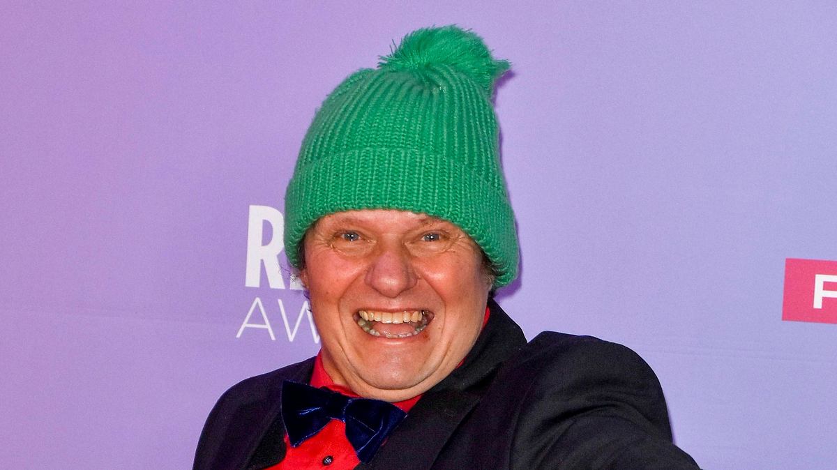 Manni Ludolf, hier mit grüner Wollmütze zu sehen, lacht breit in die Kamera.