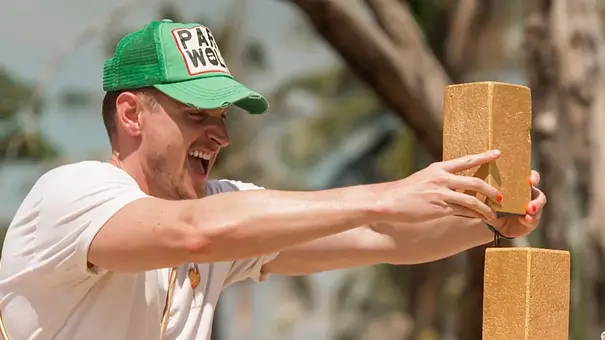 Tommy baut einen Turm mit offenem Mund und trägt eine grüne Kappe - Foto: Joyn Tommy baut einen Turm mit offenem Mund und trägt eine grüne Kappe - Foto: Joyn