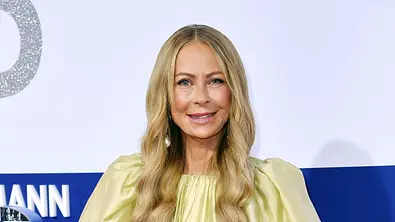 Jenny Elvers bei einem öffentlichen Event in einem hellgrünen Kleid vor einer blau-weißen Sponsorenwand. - Foto: IMAGO / APress