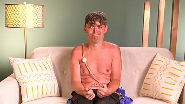 Paddy sitzt oberkörperfrei mit einem fragenden Blick und einem Haarreif in der Hand auf einem Sofa - Foto: Joyn Paddy sitzt oberkörperfrei mit einem fragenden Blick und einem Haarreif in der Hand auf einem Sofa - Foto: Joyn