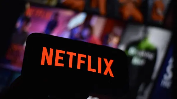 Das Netflix-Logo auf einem Smartphone vor einem Bildschirm mit Netflix-Inhalten. - Foto: IMAGO / ABACAPRESS