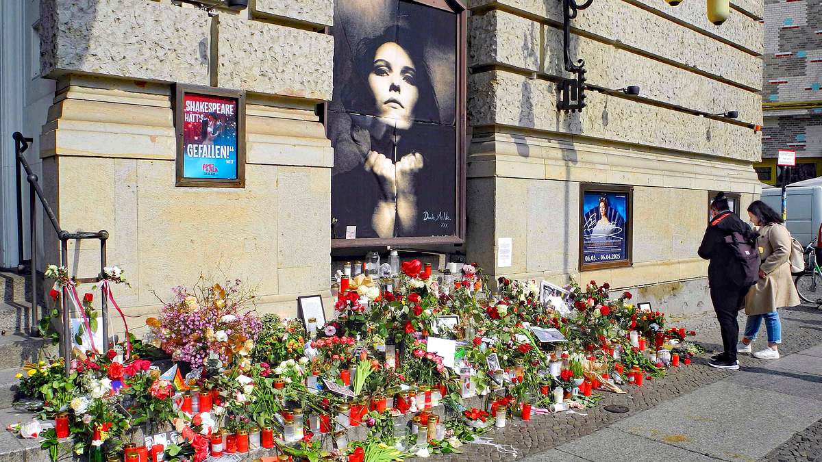 Vor dem Theater des Westens legten Fans Blumen, Kerzen und Botschaften für AnNa R. ab. Das Theater des Westens in Berlin. Ein Bild von AnNa R. ziert einen Teil der Wand, auf dem Boden liegen Blumen und Kerzen.