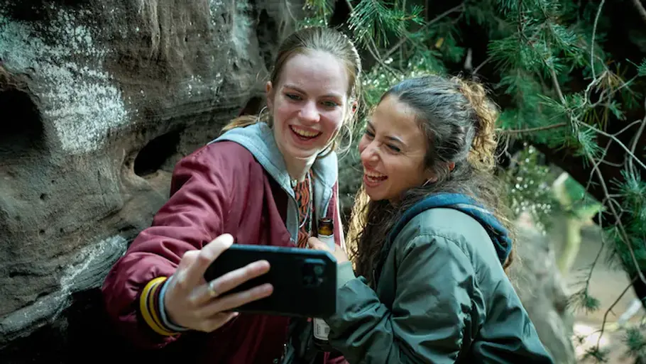 „Wäldern – Das verschwundene Mädchen“: Magda und ihre Freundin Zwei junge Mädchen stehen im Wald zwischen Felsen und machen gemeinsam ein Selfie.