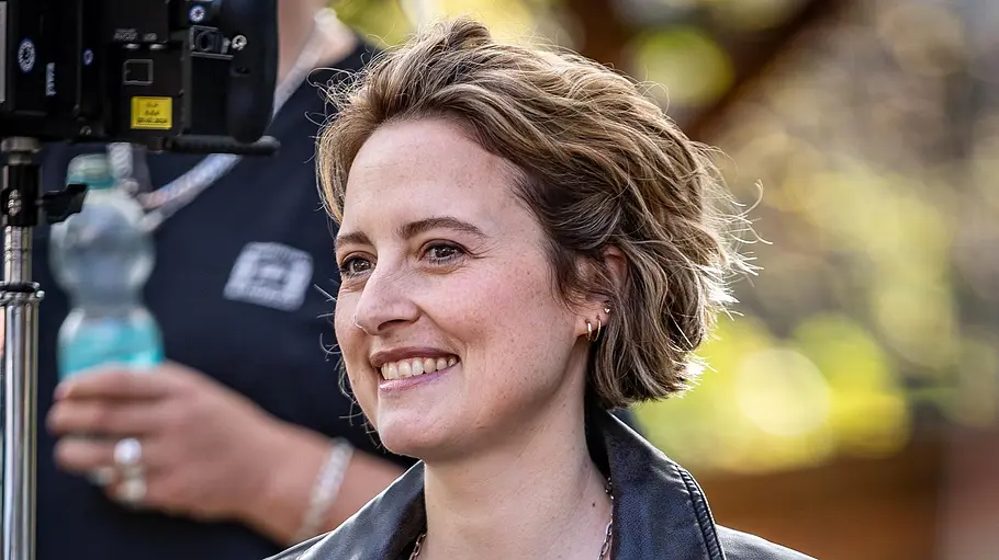 Wanda Perdelwitz Schauspielerin Wanda Perdelwitz lächelt am Filmset, während neben ihr eine Kamera aufgebaut ist.