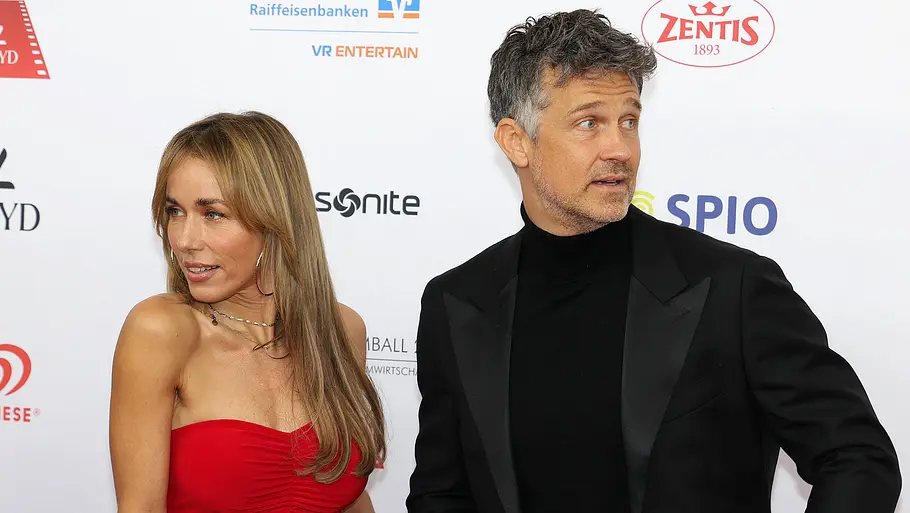 Annemarie und Wayne Carpendale News Trennungsgrund? Annemarie im roten Kleid und Wayne Carpendale im schwarzen Anzug stehen sich gegenüber und drehen sich voneinander weg.