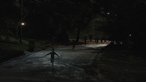 Man sieht mehrere Kinder, die in der Dunkelheit über eine Straße laufen. - Foto: Warner Bros. Pictures