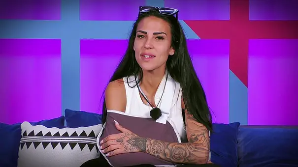 Elena Miras sitzt mit Armschlinge auf einem Sofa in einer Reality-TV-Kulisse, trägt ein weißes Oberteil, blickt ernst in die Kamera und hält ihren verletzten Arm schützend, im Hintergrund sind farbige Wandpaneele zu sehen. - Foto: RTL Elena Miras sitzt mit Armschlinge auf einem Sofa in einer Reality-TV-Kulisse, trägt ein weißes Oberteil, blickt ernst in die Kamera und hält ihren verletzten Arm schützend, im Hintergrund sind farbige Wandpaneele zu sehen. - Foto: RTL