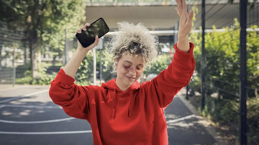 Wer einen Prepaid-Tarif mit viel Datenvolumen sucht, sollte sich das Angebot von Vodafone nicht entgehen lassen. Eine junge Frau mit Kopfhörern im Ohr und Smartphone in der Hand tanzt draußen.