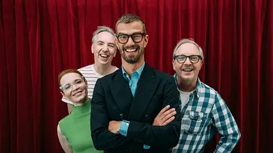 Alle Kandidat:innen der 10. Staffel Wer stiehlt mir die Show und Moderator Joko Winterscheidt stehen vor einem roten Vorhang und lächeln in die Kamera. - Foto: Joyn/Julian Mathieu