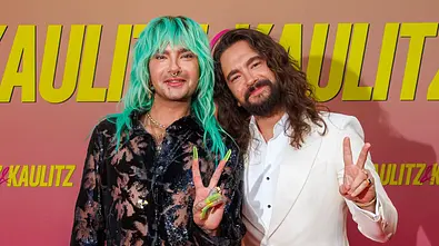 Bill und Tom Kaulitz bei der Premiere von Kaulitz und Kaulitz von Netflix, lächeln in die Kamera und machen mit der Hand ein Peace-Zeichen. - Foto: IMAGO / Eventpress