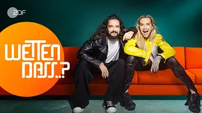 Tom und Bill Kaulitz sitzen nebeneinander auf einer roten Couch. Tom legt seine Arm auf die Schulter von Bill. Beide schauen in die Kamera. Im linken Bildrand steht das Logo von Wetten, dass in einem orangefarbenen Kreis. - Foto: ZDF und Rankin