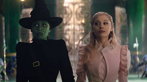 Man sieht Cynthia Erivo und Ariana Grande als Elphaba und Glinda in „Wicked“. Erivo ist grün und trägt eine schwarze Hexenrobe, während Grande ein leichtes Rosa aufträgt. Der Hintergrund ist in Smaragd-Grün. Man sieht die Affen-Wachen des Zauberers von Oz.  - Foto: IMAGO / Landmark Media