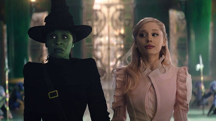 Man sieht Cynthia Erivo und Ariana Grande als Elphaba und Glinda in „Wicked“. Erivo ist grün und trägt eine schwarze Hexenrobe, während Grande ein leichtes Rosa aufträgt. Der Hintergrund ist in Smaragd-Grün. Man sieht die Affen-Wachen des Zauberers von Oz.  - Foto: IMAGO / Landmark Media