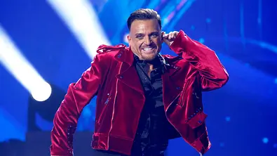 Menowin in roter Jacke mit Mikrofon. - Foto: IMAGO / Panama Pictures