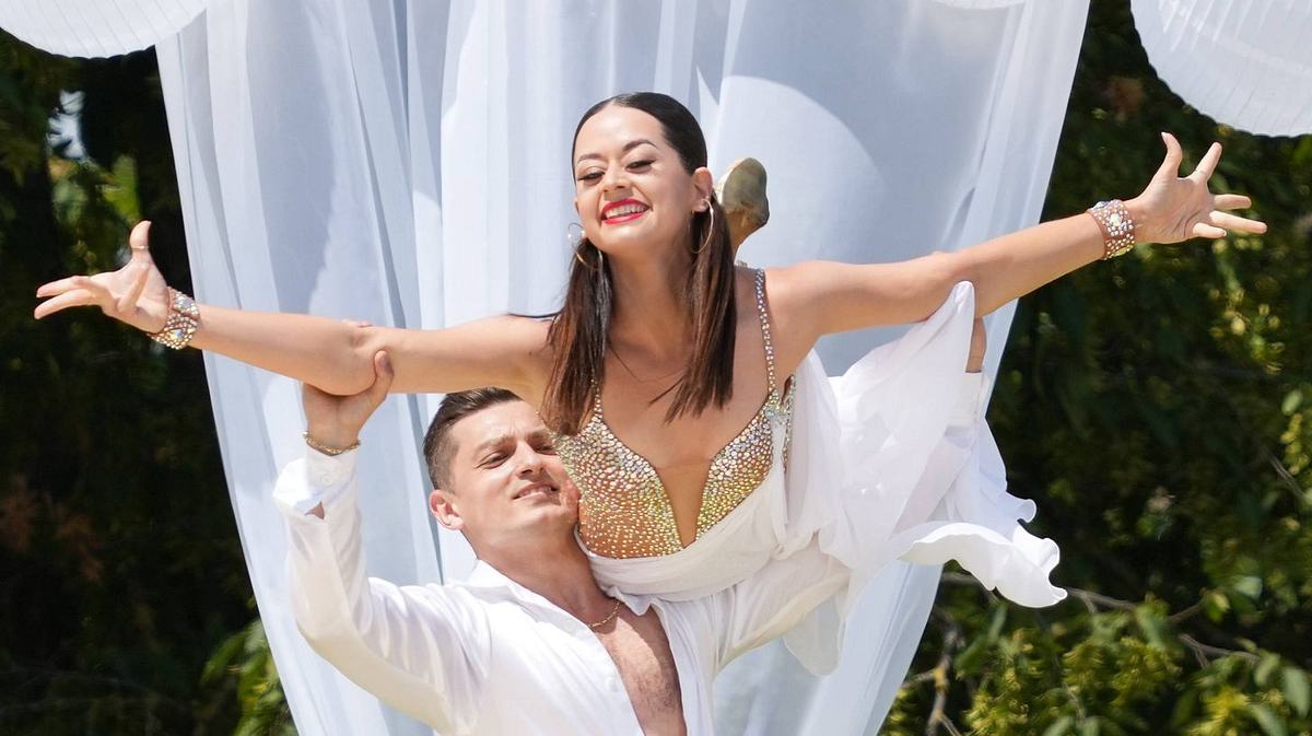 Zsolt spricht über neue Freundin und Malika Zsolt Sándor Cseke und Ex-Freundin Malika Dzumaev bei einem Tanzauftritt ganz in weiß. Er hebt sie bei einer Hebefigur in die Luft, sie breitet die Arme aus und lächelt.