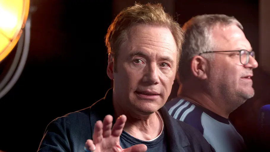 Will Bully einfach das Comedyformat wechseln? Bully im Interview, er hebt eine Hand, hinter ihm steht Elton.
