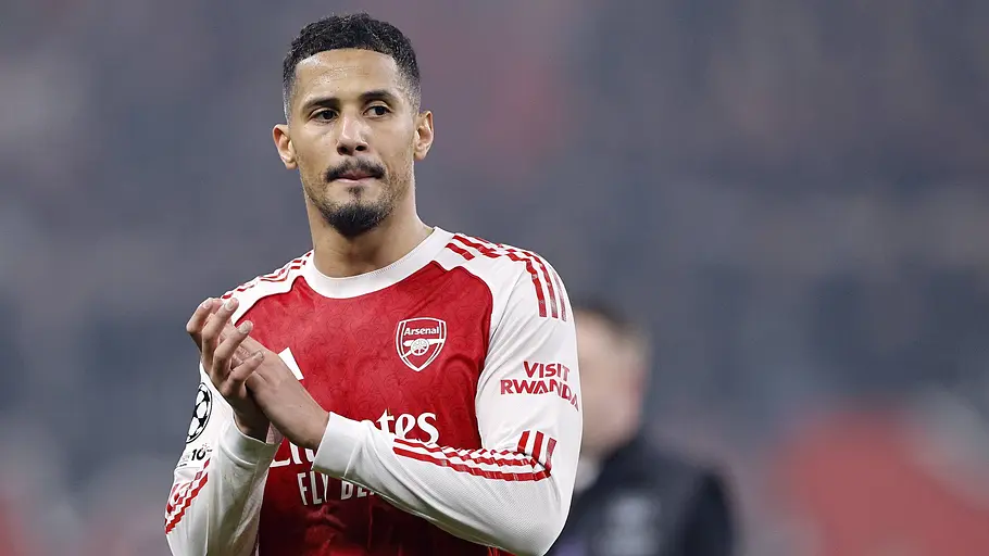 Arsenal-Verteidiger William Saliba applaudiert nach einem Spiel im roten Heimtrikot des FC Arsenal. Im Hintergrund ist das Stadion unscharf zu erkennen.