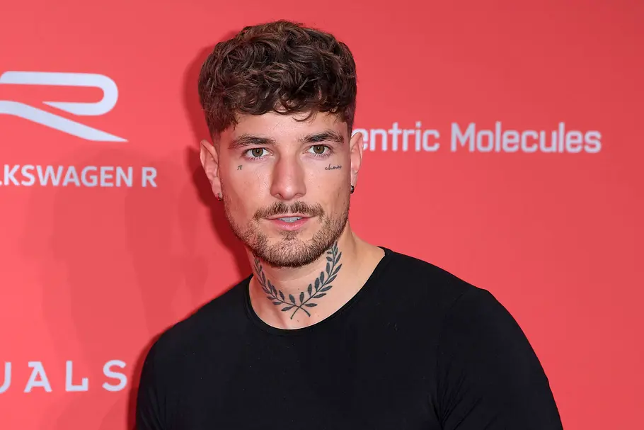 Willy Whey am Red Carpet Willi Whey steht vor einem roten Banner bei den GQ Men of the Year Awards
