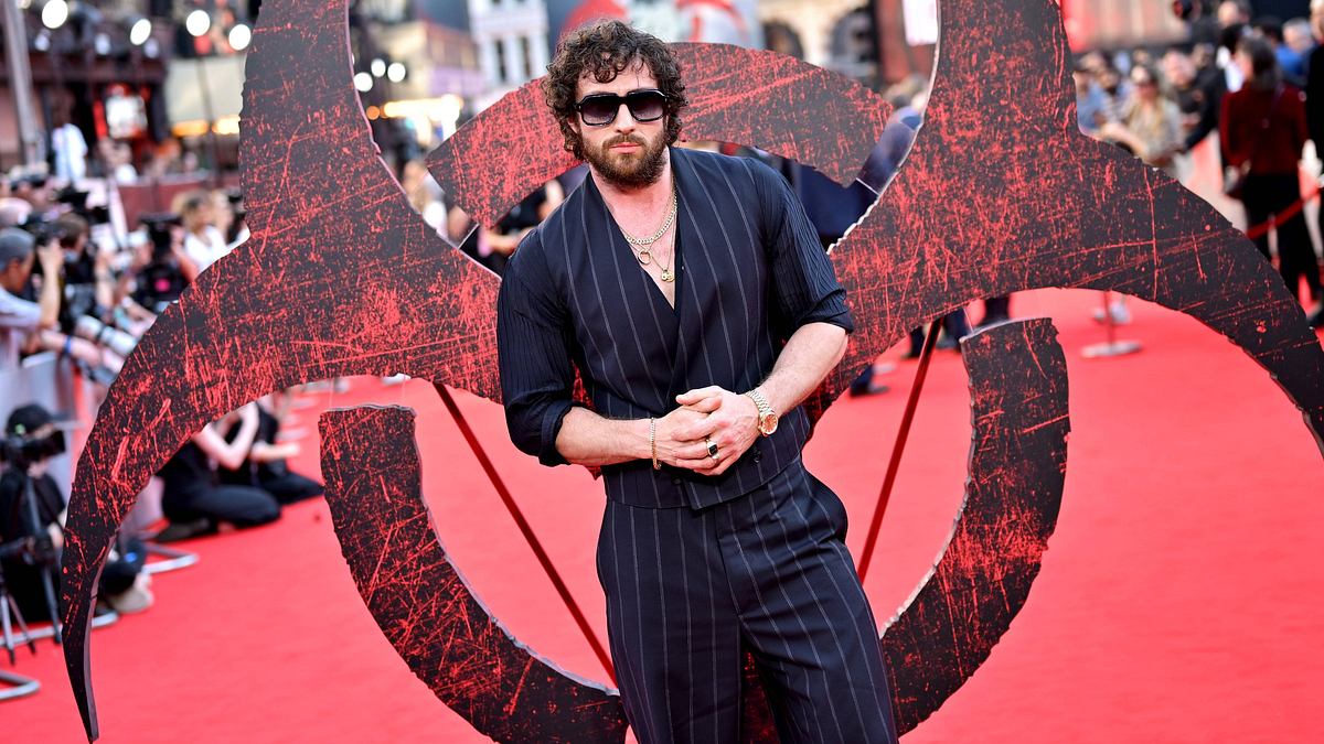 Aaron Taylor-Johnson Aaron Taylor-Johnson trägt ein schwarz-weiß gestreiftes Fit auf einem Red Carpet für den Film „28 Years Later“. Hinter ihm ist ein großes Infektionssymbol.