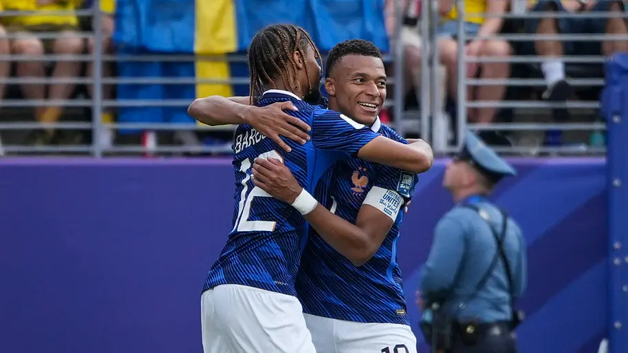 Mbappe und Barcola liegen sich nach einem Tor in den Armen und lächeln.