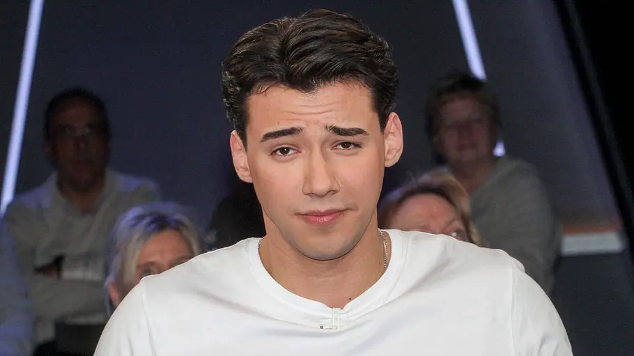 Diego Pooth ist umgezogen. Diego Pooth trägt ein weißes T-Shirt und schaut mit hochgezogener Stirn in die Kamera.