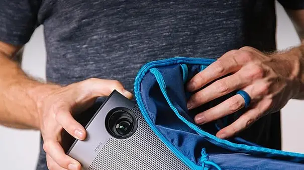 Eine Hand zieht den XGIMI Beamer aus einer Tasche. - Foto: TV Movie / Amazon / XGIMI Eine Hand zieht den XGIMI Beamer aus einer Tasche. - Foto: TV Movie / Amazon / XGIMI