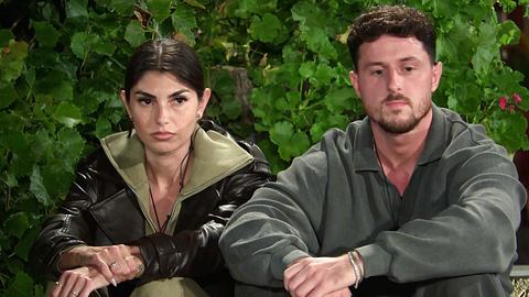 Yeliz Koc und Jannik Kontalis sitzen nebeneinander, sie schauen angespannt nach vorne. - Foto: RTL
