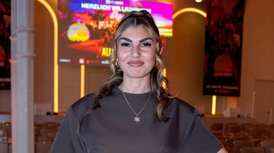 Yeliz Koc Yeliz Koc trägt ein braunes Kleid und lächelt in die Kamera.