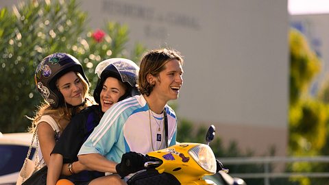 Drei Teenager aus der Netflix-Serie Young Millionaires sitzen auf einem Moped und wirken glücklich - Foto: Netflix