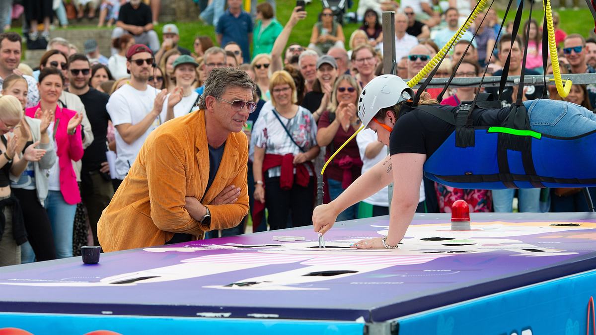 Hans Sigl lässt Laura Haering bei einem Spiel nicht aus den Augen. Hans Siegel schaut Laura Haering dabei zu, wie sie in der Luft hängt und ein Spiel spielt.