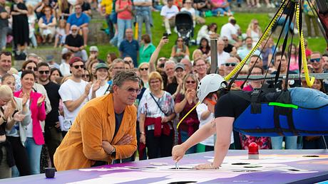 Hans Siegel schaut Laura Haering dabei zu, wie sie in der Luft hängt und ein Spiel spielt. - Foto: ZDF / Ralph Orlowski