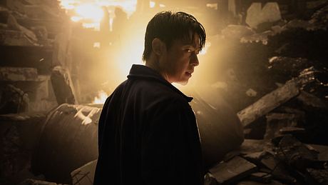 Sing steht mit dem Rücken zur Kamera und schaut mit einem strengen Blick nach vorne. - Foto: Courtesy of Netflix